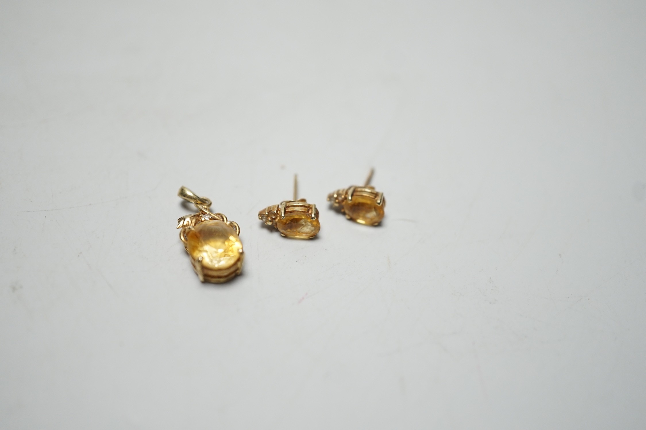 A modern 14k, citrine and diamond chip set pendant, 15mm and a pair of matching ear studs, gross weight 3.1 grams.